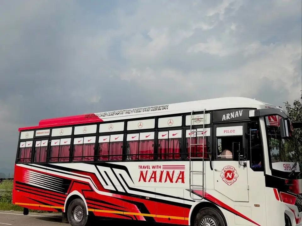 Semi-deluxe bus, red and white livery, front three-quarter view on the road — built by Guru Kirpa Bus Body Builders, Barnala